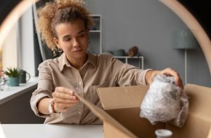 تصویری از یک فرد در حال بسته بندی لوازم شکننده با استفاده از کارتن پستی