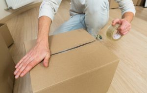 تصویری از فردی در حال بسته بندی با استفاده از کارتن پستی