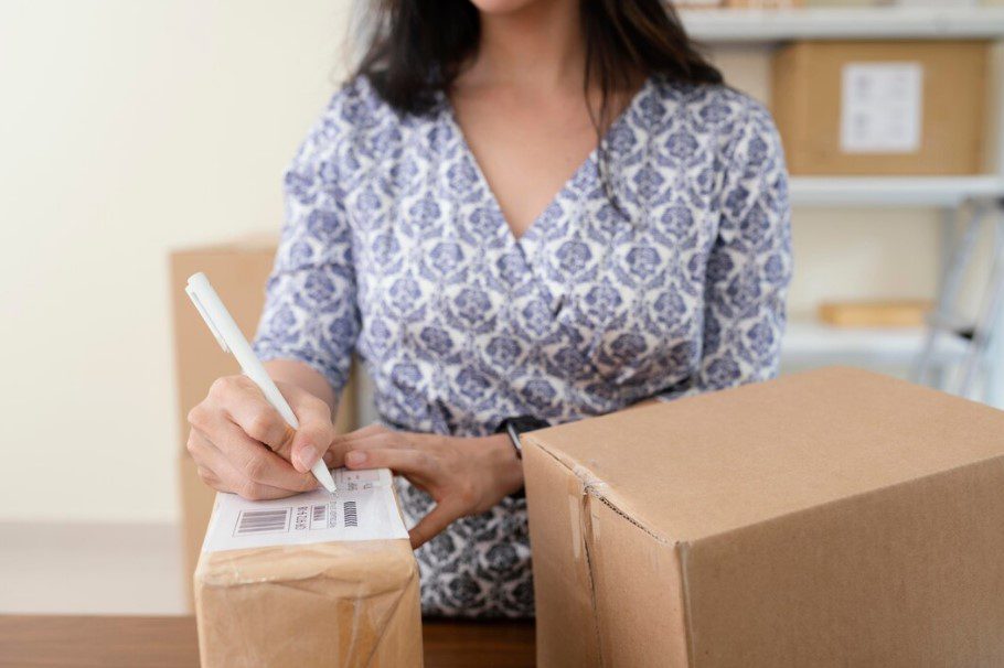 تصویری از زنی در حال بستهبندی وسایل خود با سایز مناسب کارتن پستی و بستهبندی